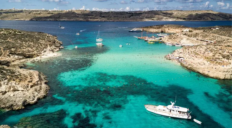 Aerial view of the turquoise Blue Lagoon channel between Comino and Cominotto with moored boats