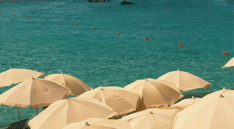 Cream beach umbrellas above the turquoise water of the Blue Lagoon in Malta